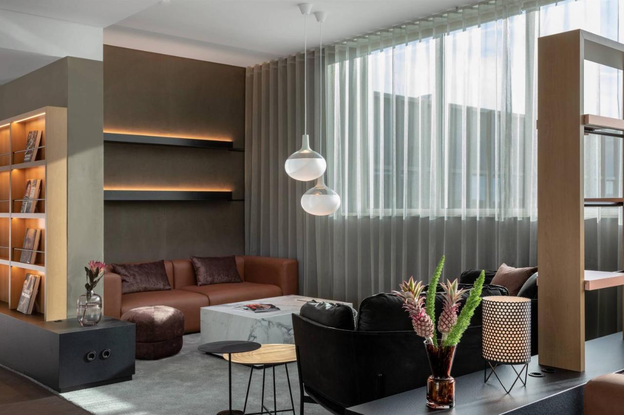 Frankfurt Airport Marriott Hotel فرانكفورت المظهر الخارجي الصورة The photo depicts a modern living room with a stylish and contemporary design. Key features include:

- A cozy brown sofa and a black armchair for seating.
- A light-colored coffee table in the center, surrounded by various decor elements.
- A wall w