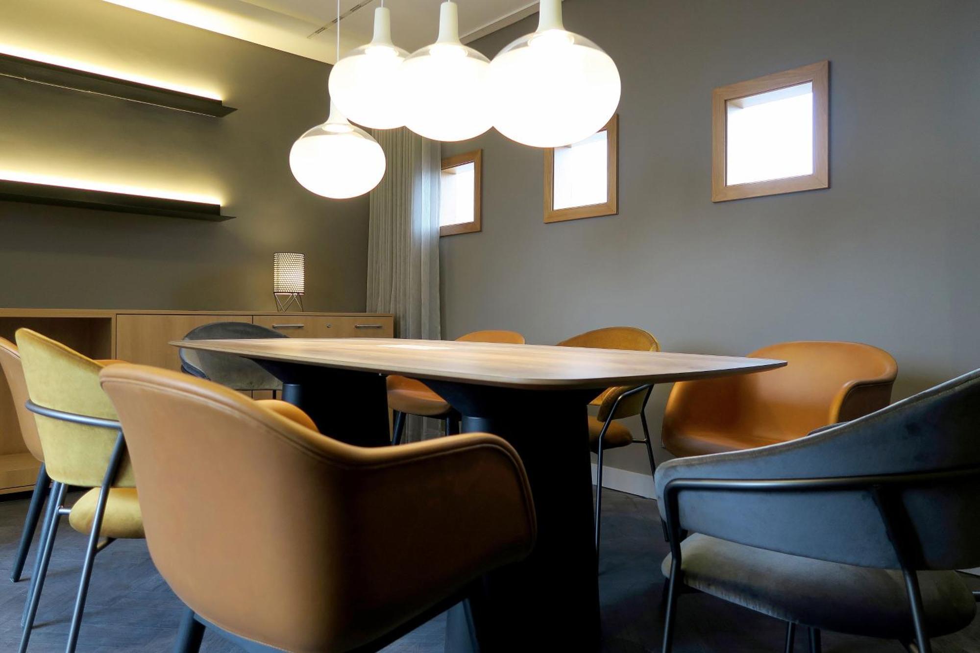 Frankfurt Airport Marriott Hotel فرانكفورت المظهر الخارجي الصورة The photo shows a modern conference or meeting room. It features a stylish table at the center, surrounded by several ergonomic chairs in varying colors, including shades of yellow and grey. Above the table, there are three round pendant light fixtur