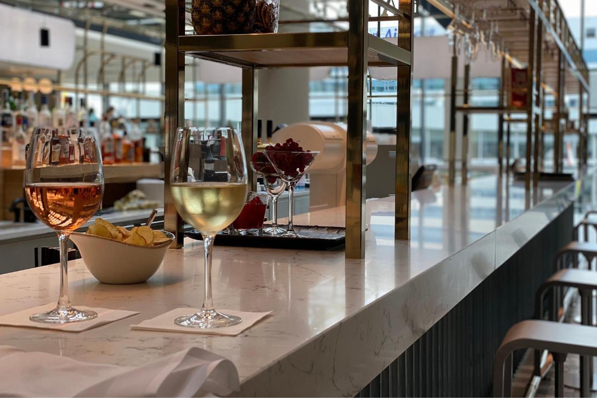 Frankfurt Airport Marriott Hotel فرانكفورت المظهر الخارجي الصورة The photo shows a bar setting with a smooth, light-colored marble countertop. There are two glasses placed on coasters: one contains a light-colored beverage, likely white wine or sparkling wine, and the other has a darker, amber drink, possibly a co